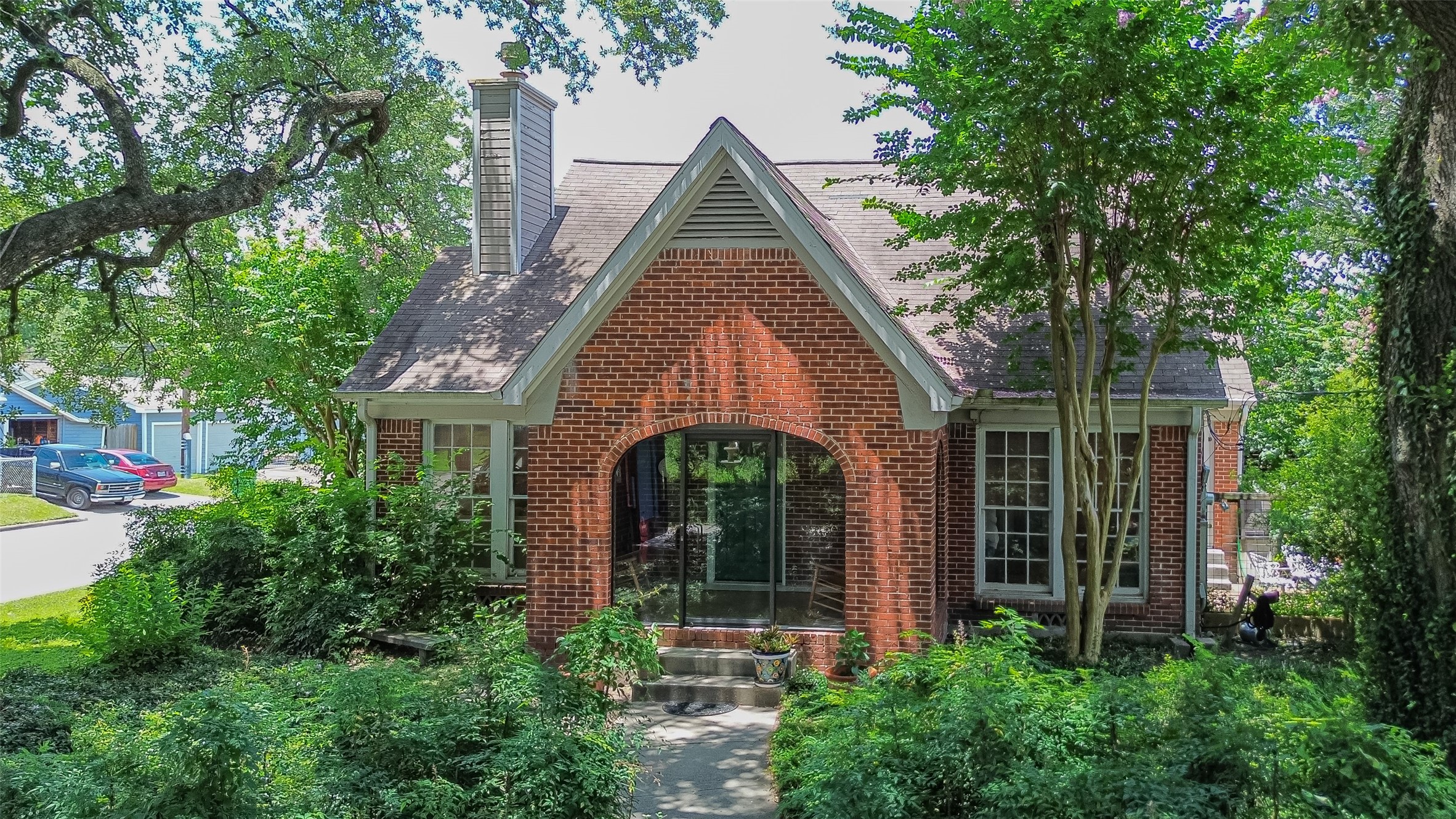 a view of a brick house with large windows and a large tree