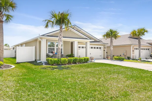 a view of a house with a yard and palm trees