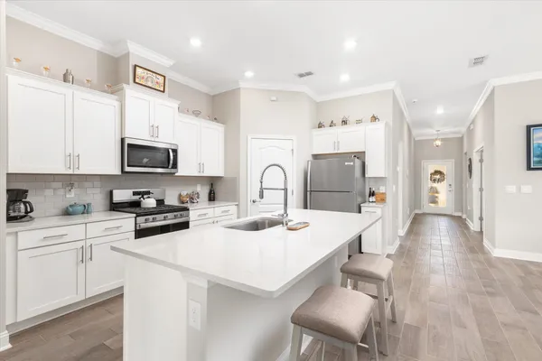 a kitchen with stainless steel appliances white cabinets a sink and a refrigerator