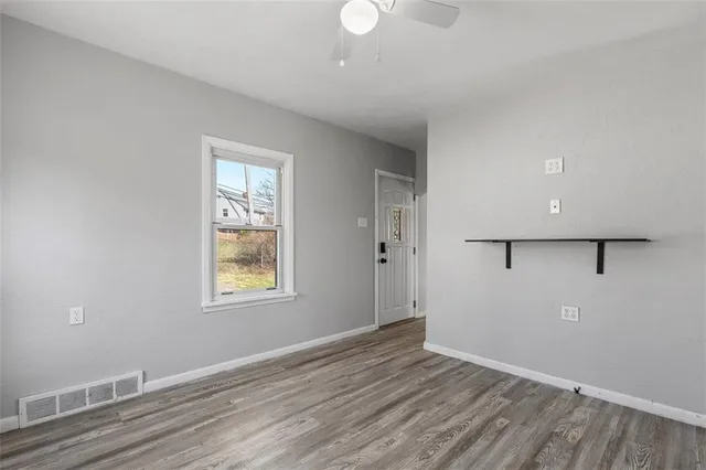 an empty room with wooden floor and windows