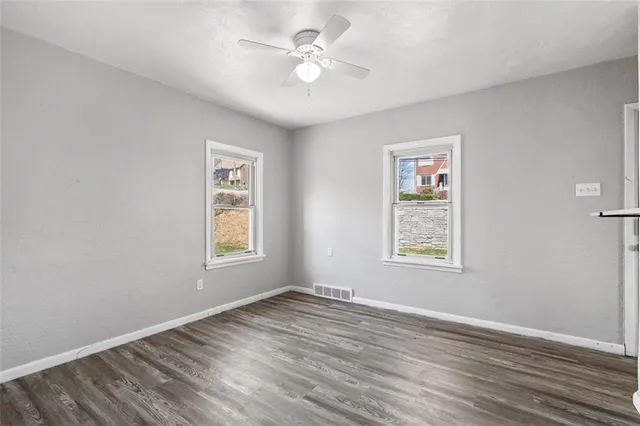 a view of an empty room with a window and wooden floor