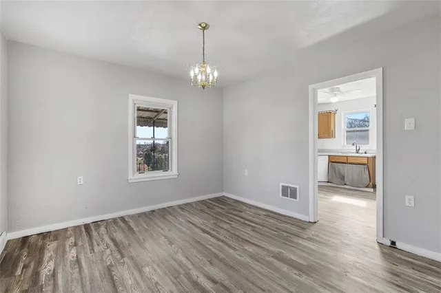 a view of a room with wooden floor a ceiling fan and windows