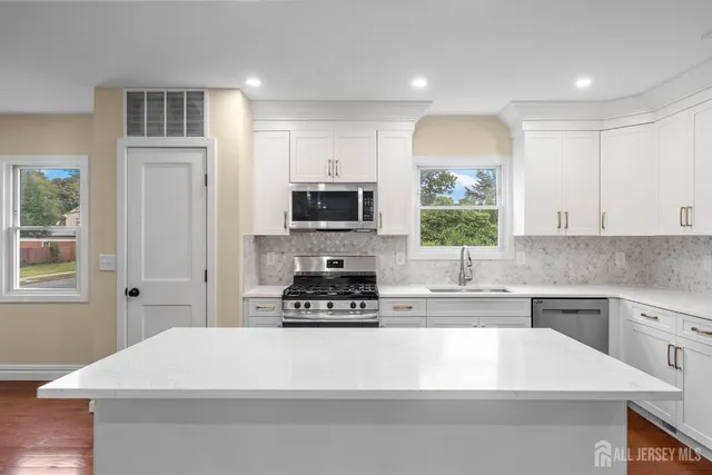 a kitchen with a refrigerator a stove top oven a sink and cabinets