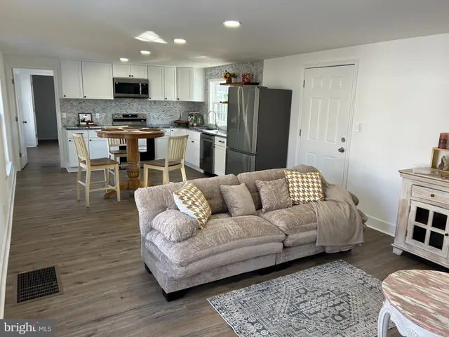 a living room with furniture and a dining table with wooden floor