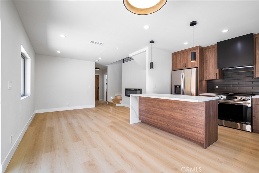 11431 De Celis Place Granada Hills, CA 91344 - Photo 6 of 20 a kitchen with stainless steel appliances granite countertop a sink a stove and a wooden floors