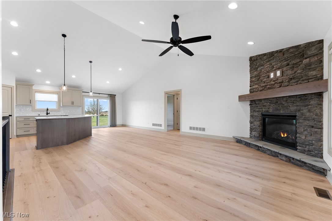 8664 Akron Road Marshallville, OH 44645 - Photo 10 of 29 Unfurnished living room featuring light hardwood / wood-style floors, sink, ceiling fan, high vaulted ceiling, and a fireplace