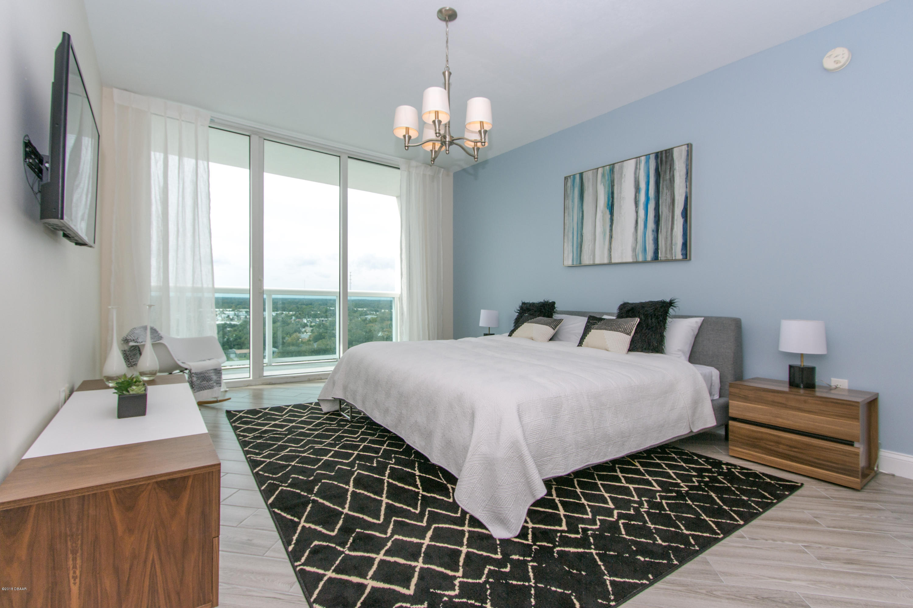 241 Riverside Drive, Unit 1409 Holly Hill, FL 32117 - Photo 13 of 35 a bedroom with a large bed and a chandelier
