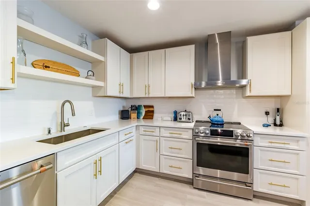 a kitchen with stainless steel appliances granite countertop white cabinets and a stove a refrigerator with white cabinets
