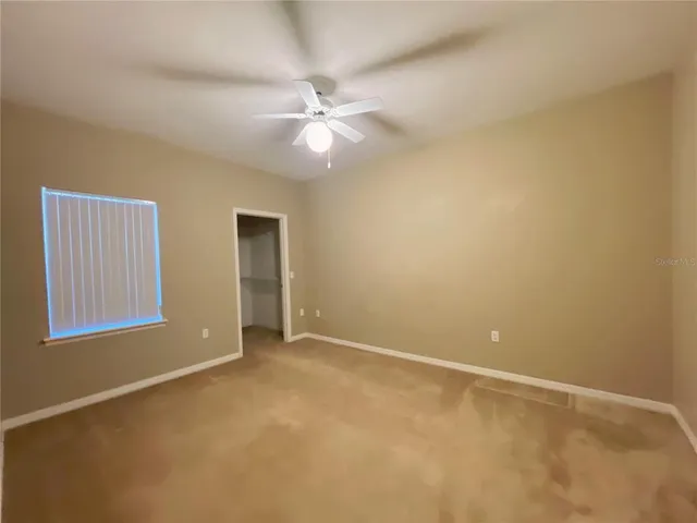 an empty room with a fan & a window