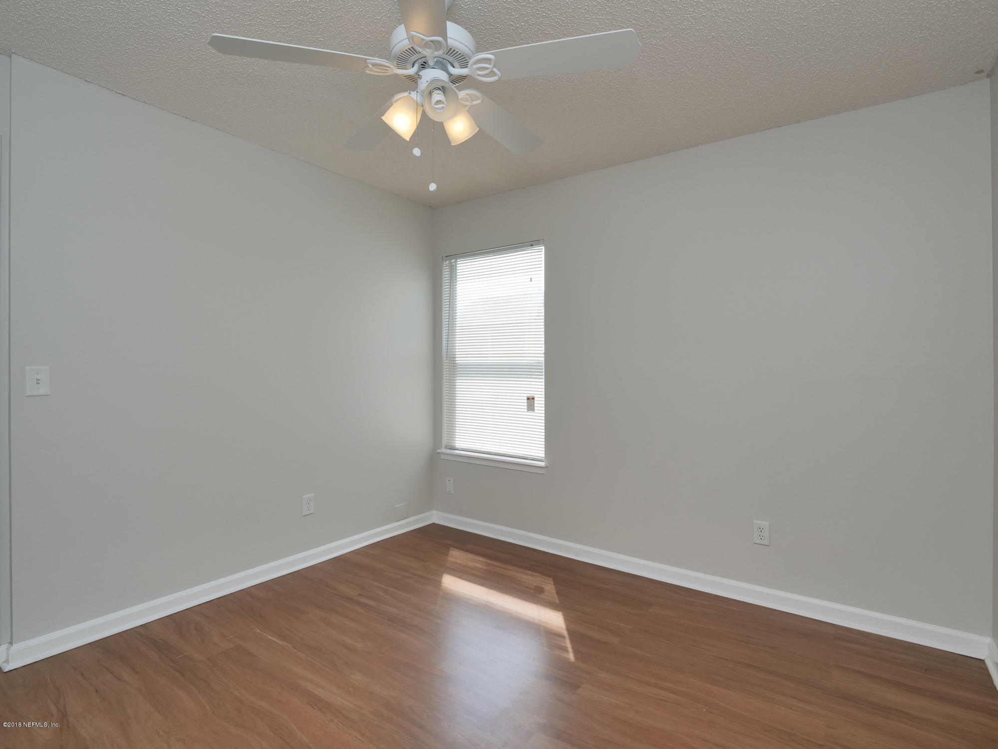 2448 Spring Vale Road Jacksonville, FL 32246 - Photo 20 of 24 an empty room with wooden floor and window