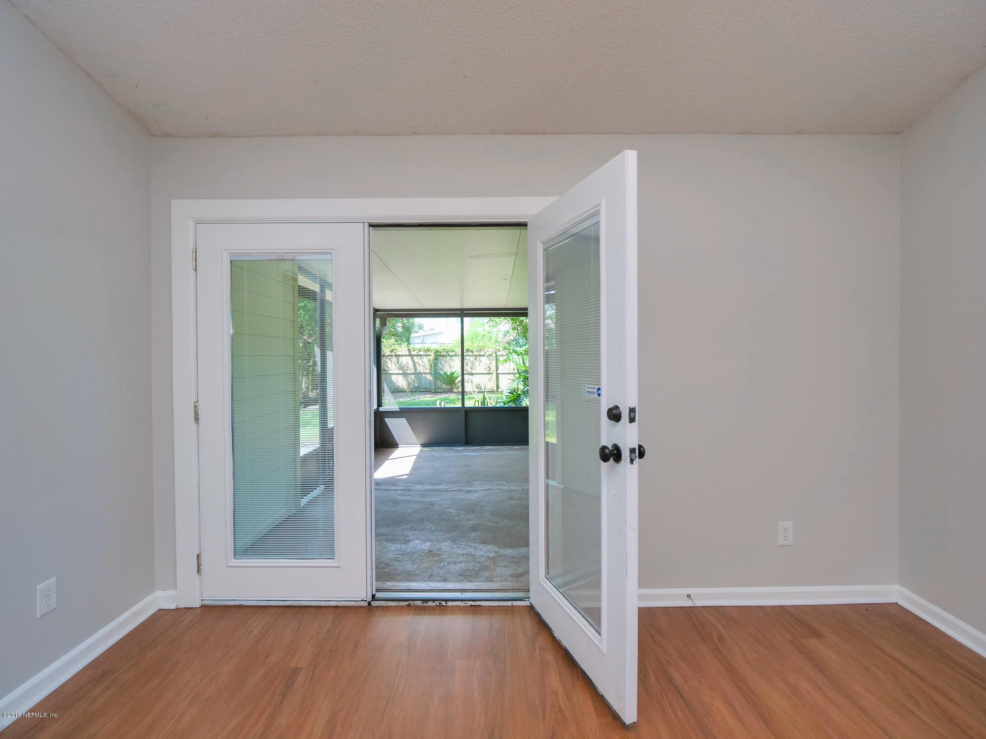 2448 Spring Vale Road Jacksonville, FL 32246 - Photo 7 of 24 an empty room with wooden floor mirror and windows