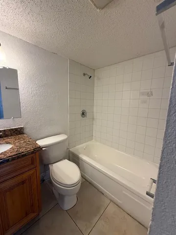 a bathroom with a granite countertop toilet a sink and bathtub