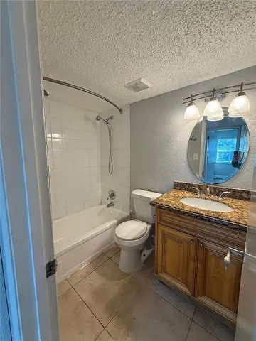 a bathroom with a granite countertop toilet sink and mirror