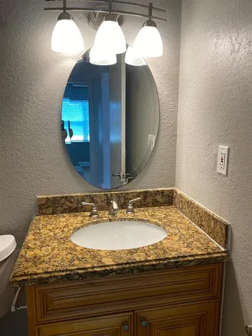 a bathroom with a granite countertop sink and a mirror