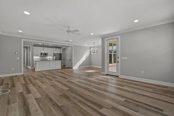 a view of empty room with kitchen and refrigerator