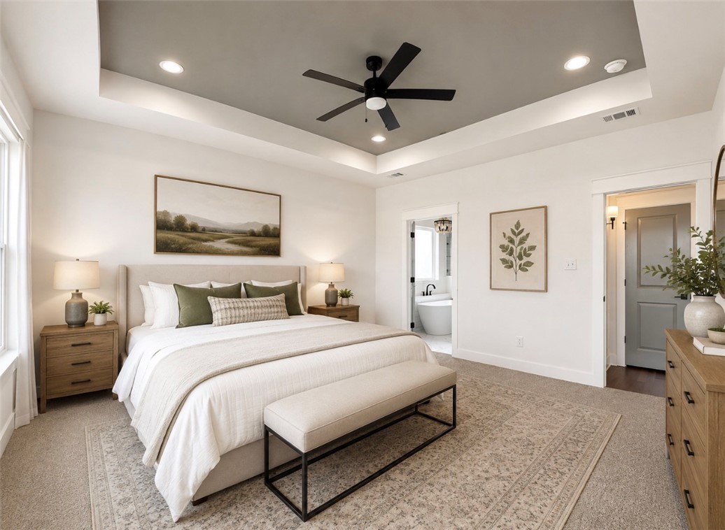 3245 Hunters Crossing Bryan, TX 77808 - Photo 9 of 30 Spacious bedroom featuring a tray ceiling with recessed lighting, black ceiling fan, light-toned carpeting, and a doorway to an adjacent bathroom with a freestanding tub