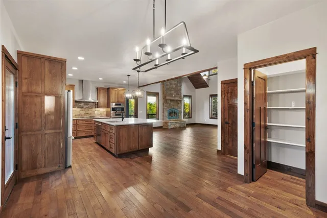 a kitchen with stainless steel appliances granite countertop a refrigerator a sink dishwasher a stove and a wooden floor