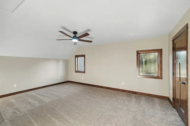 an empty room with ceiling fan and windows