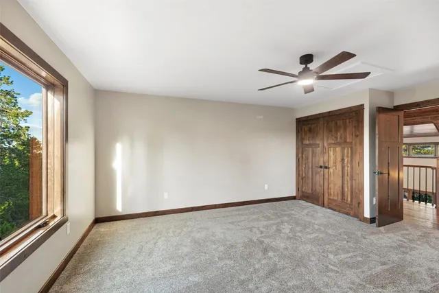 an empty room with ceiling fan and windows