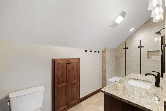a bathroom with a granite countertop sink a toilet and shower