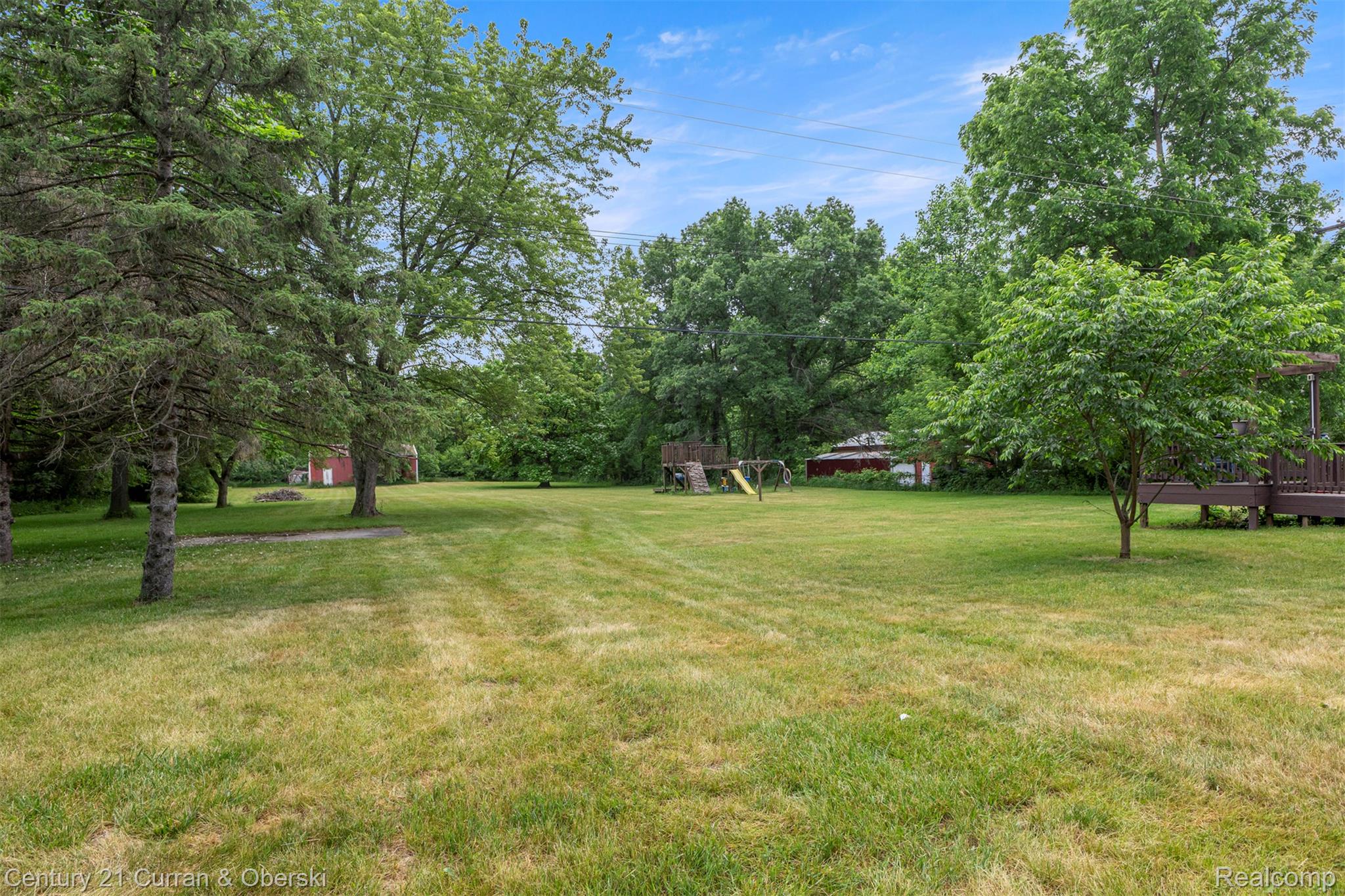 18491 Savage Road Belleville, MI 48111 - Photo 36 of 49 Expansive green lawn with mature trees and a rear deck