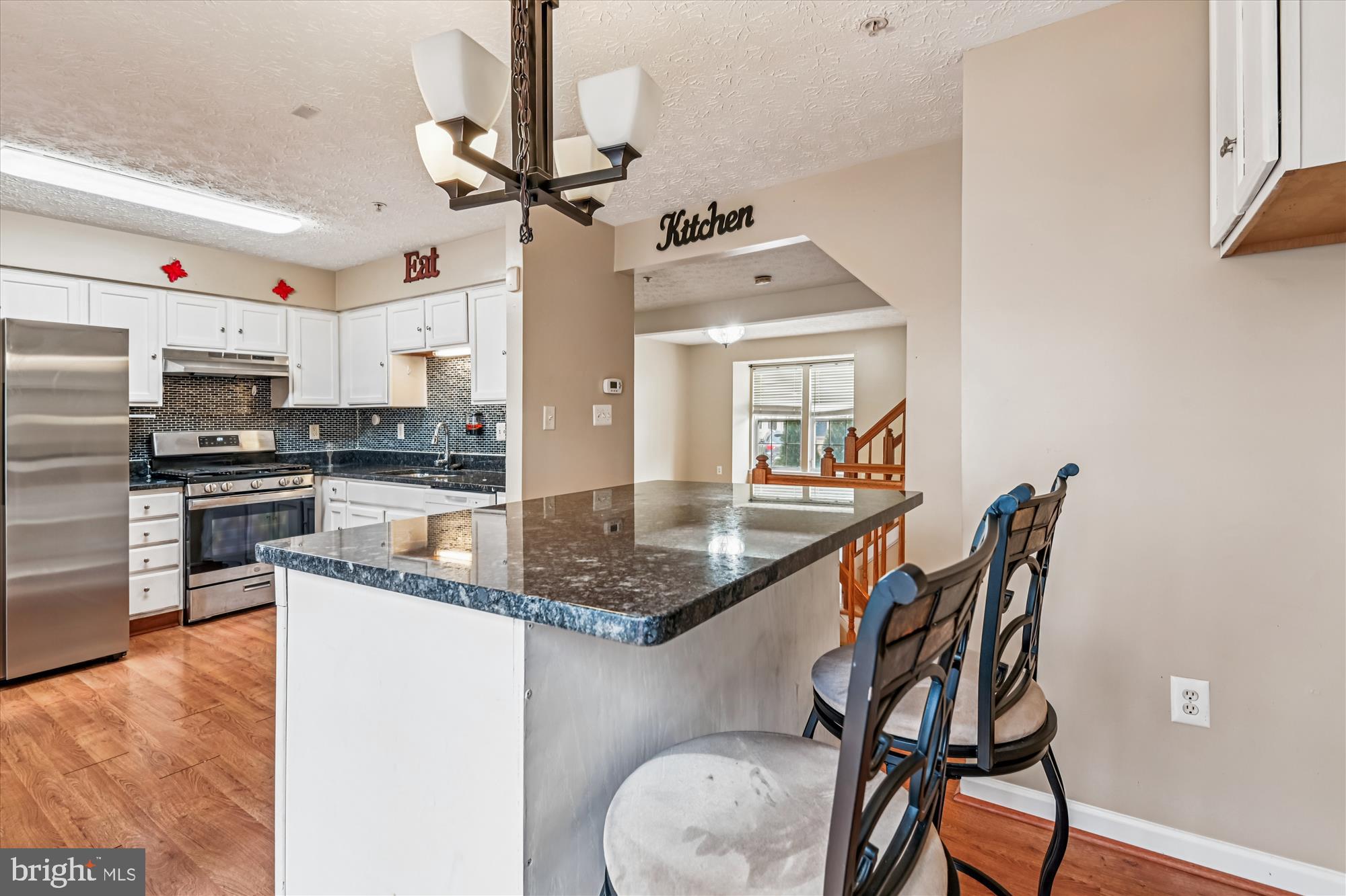 8018 Brookmead Court Severn, MD 21144 - Photo 12 of 35 a kitchen with stainless steel appliances granite countertop a stove top oven a sink a dining table and chairs with wooden floor