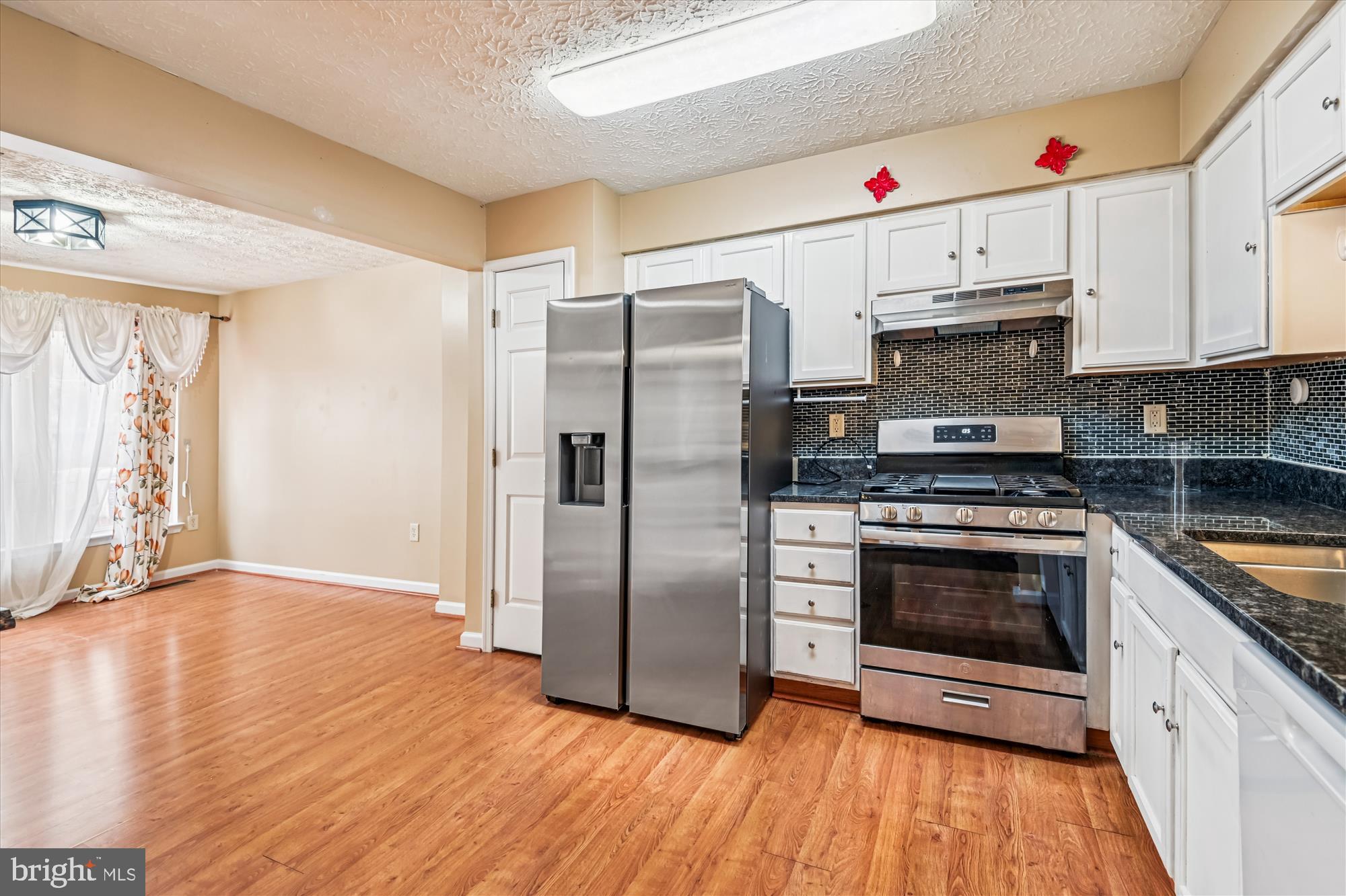 8018 Brookmead Court Severn, MD 21144 - Photo 7 of 35 a kitchen with granite countertop a refrigerator and a stove top oven