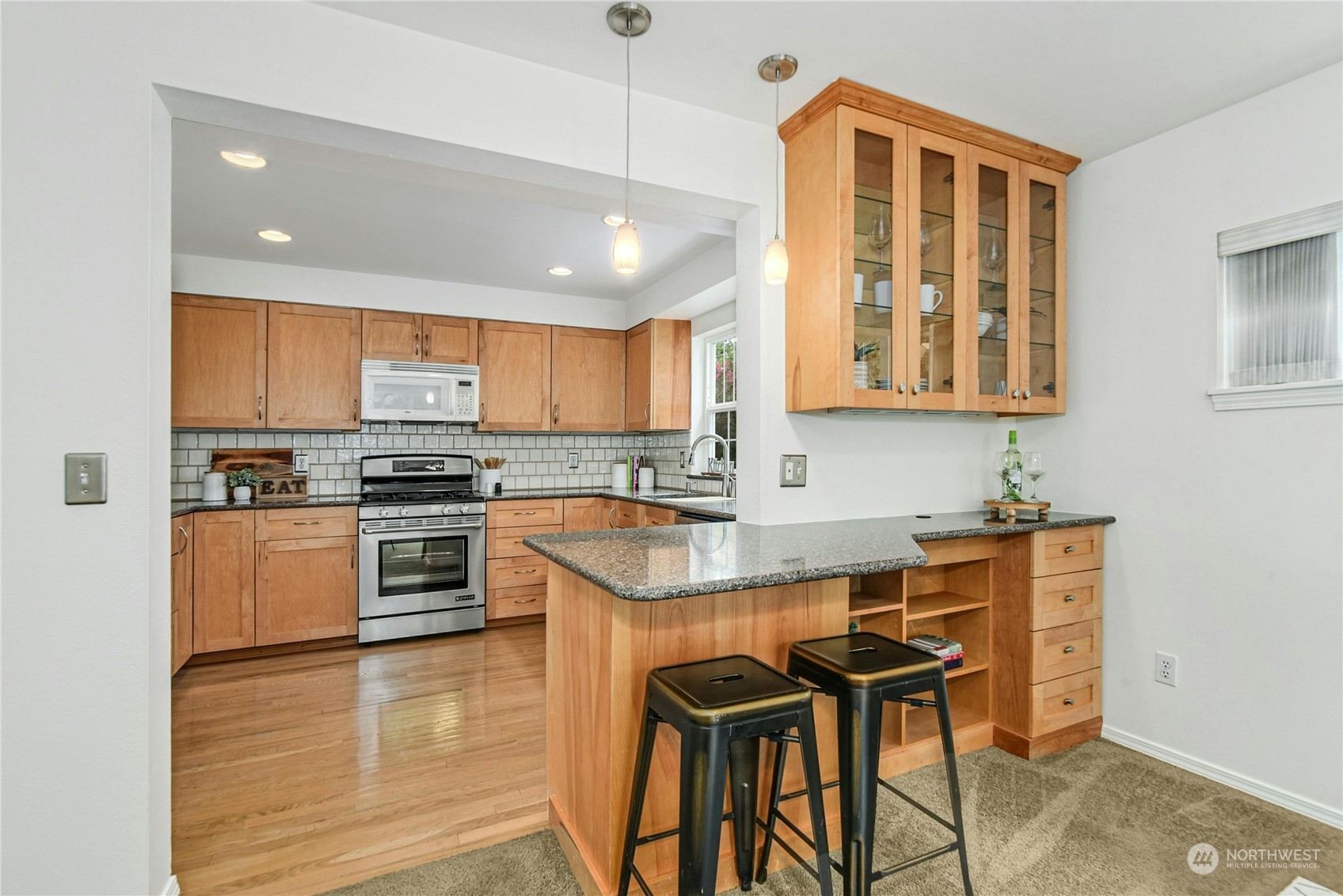 1310 North 41st Street, Unit B Seattle, WA 98103 - Photo 8 of 40 a kitchen with stainless steel appliances granite countertop a stove top oven a sink a dining table and chairs with wooden floor