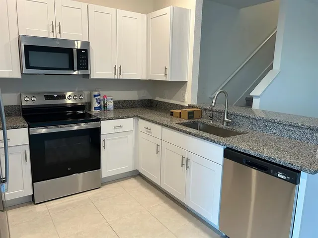 a kitchen with granite countertop white cabinets and stainless steel appliances