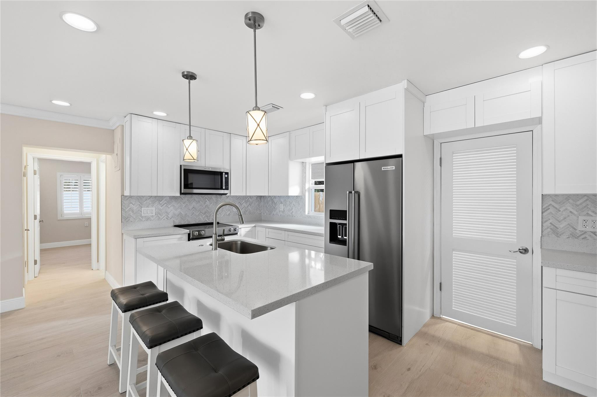 2000 Northeast 17th Street Fort Lauderdale, FL 33305 - Photo 26 of 44 a kitchen with kitchen island white cabinets and stainless steel appliances