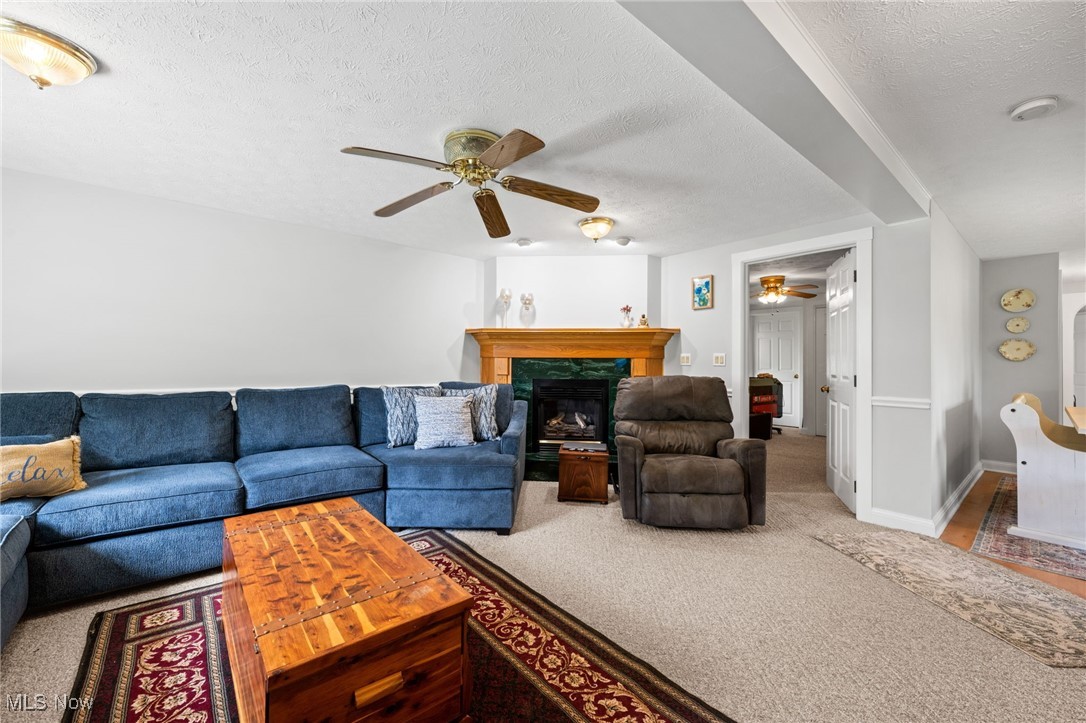 3945 Columbia Road Medina, OH 44256 - Photo 12 of 40 Living room featuring a ceiling fan, a textured ceiling, carpet floors, and a fireplace