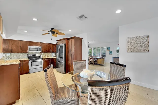 a kitchen with stainless steel appliances kitchen island granite countertop a refrigerator a stove a sink dishwasher with a dining table and chairs