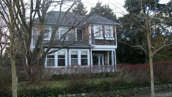 a view of a brick house next to a yard with large trees