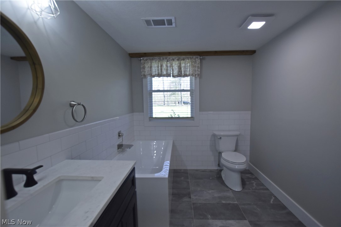 6770 Akron Peninsula Road Peninsula, OH 44264 - Photo 29 of 35 Bathroom featuring tile walls, a bath, toilet, tile flooring, and vanity