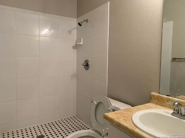 a bathroom with a granite countertop sink toilet and shower