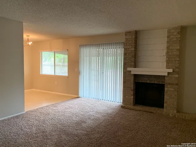 a view of an empty room with a fireplace and a window