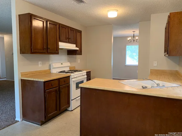 a kitchen with a sink dishwasher and a stove with wooden floor
