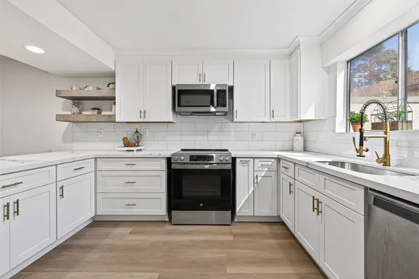 a kitchen with stainless steel appliances granite countertop a stove a sink and a microwave