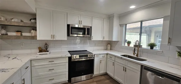 a kitchen with white cabinets a sink and stainless steel appliances