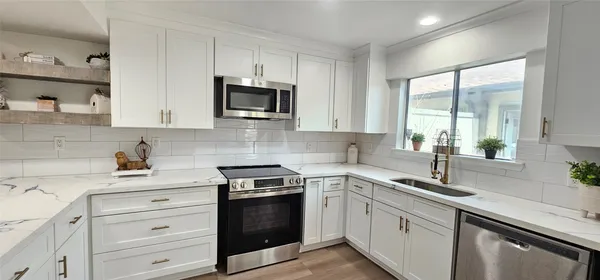 a kitchen with white cabinets and appliances