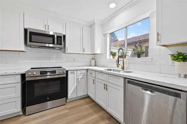 a kitchen with stainless steel appliances granite countertop a sink a stove a microwave and wooden cabinets