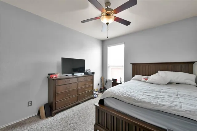 a bedroom with a bed a desk and chair with window