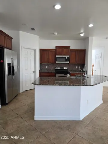 a large kitchen with stainless steel appliances granite countertop a refrigerator and a stove top oven