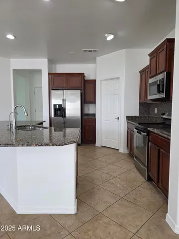 a kitchen with stainless steel appliances granite countertop a stove a sink and a refrigerator