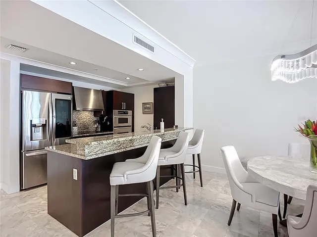 a dining hall with stainless steel appliances granite countertop a table and chairs