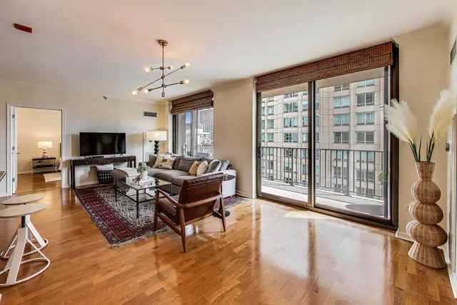 a living room with furniture a flat screen tv and a floor to ceiling window