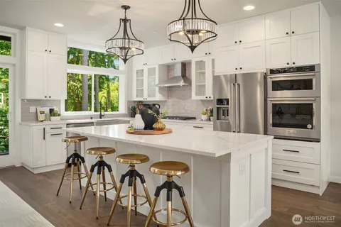 a kitchen with stainless steel appliances a table chairs refrigerator and microwave