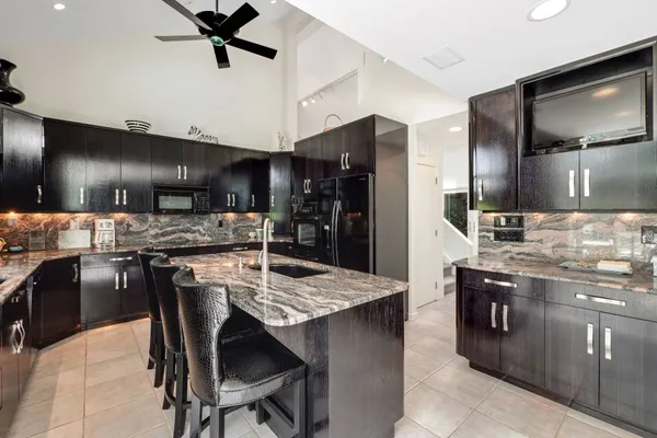 a kitchen with stainless steel appliances kitchen island granite countertop a table chairs sink and refrigerator