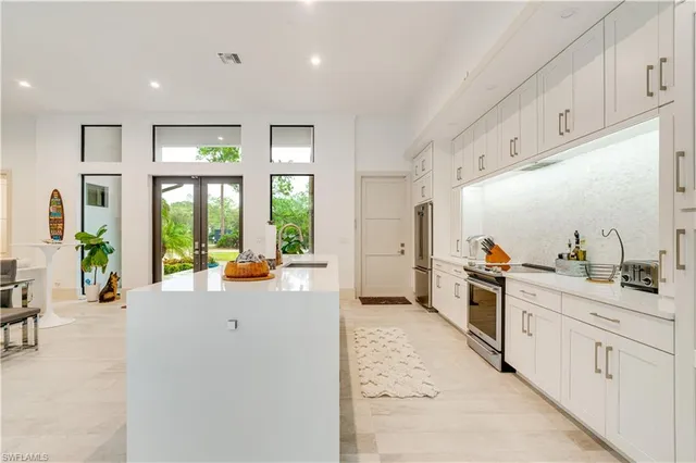 a large white kitchen with cabinets a sink a refrigerator a stove and a window