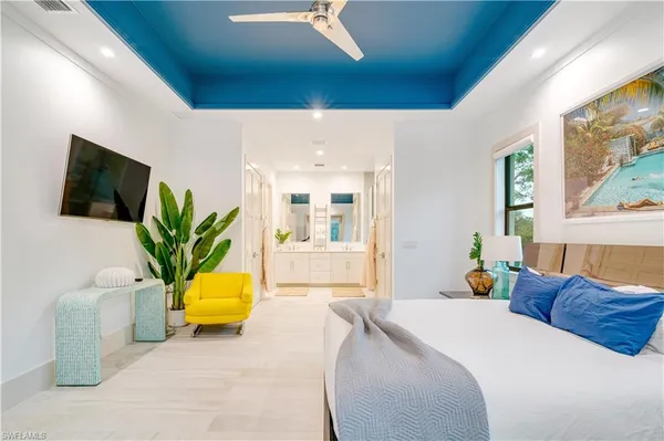 a bedroom with a bed a couch and a flat tv screen on dresser